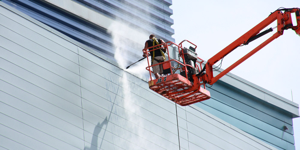 photograph of a man power washing the side of a building