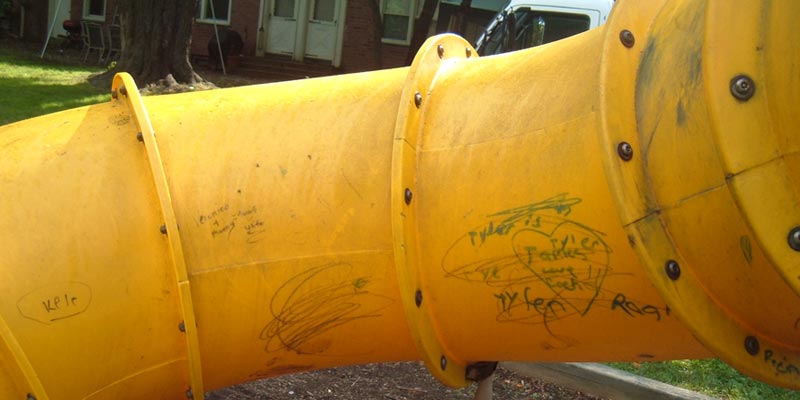 image of graffiti scrawled across a slide on a children's playground