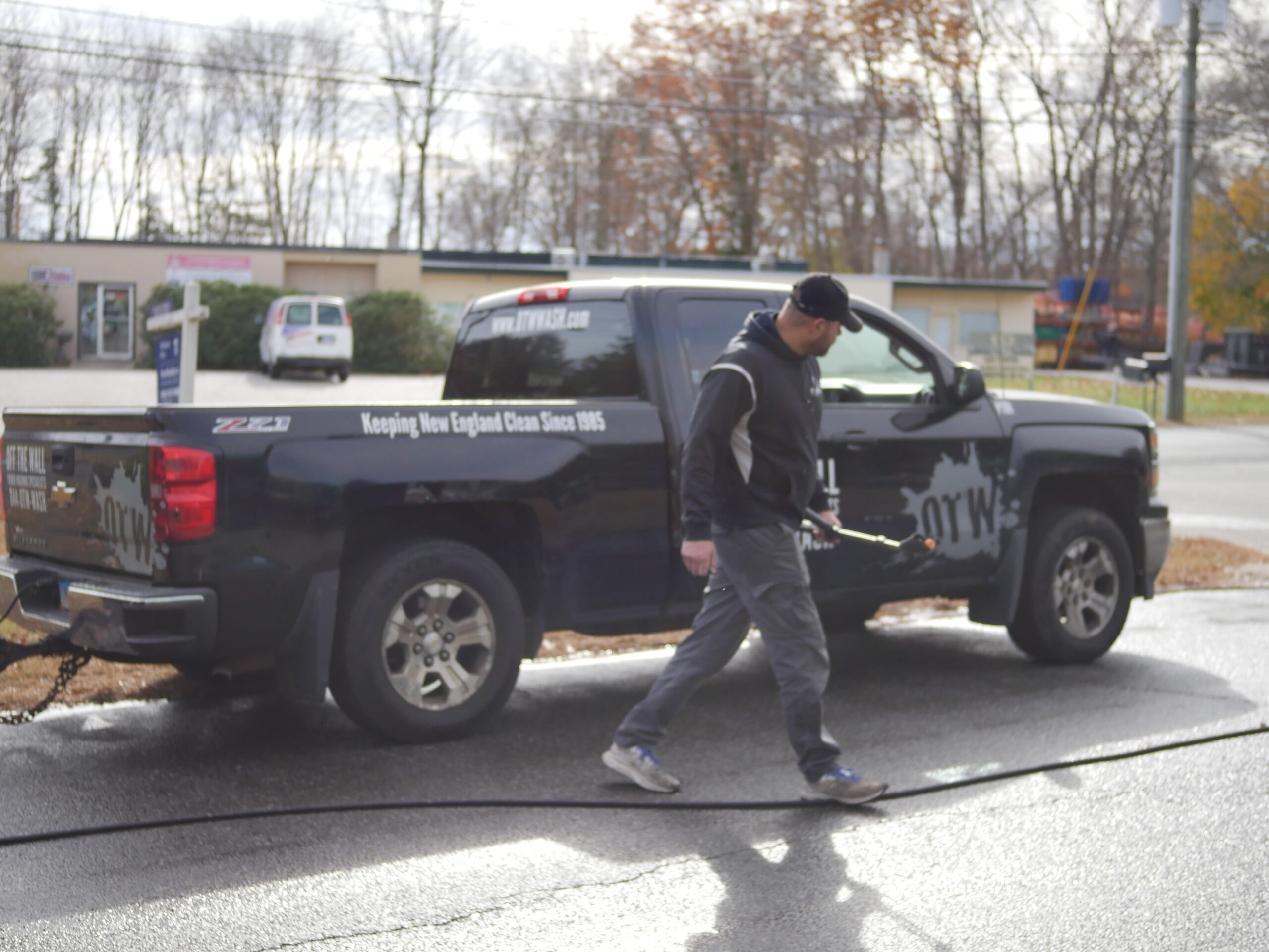 photo of an OFF THE WALL Power Washing team member walking by the branded truck
