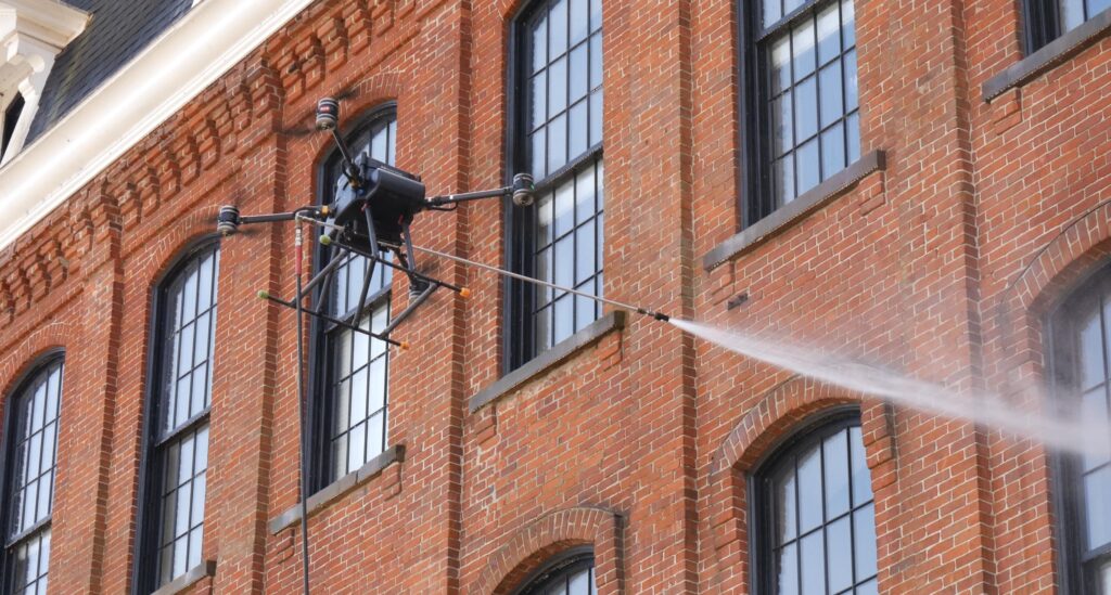 photograph of the OFF THE WALL Power Washing drone cleaning a building exterior