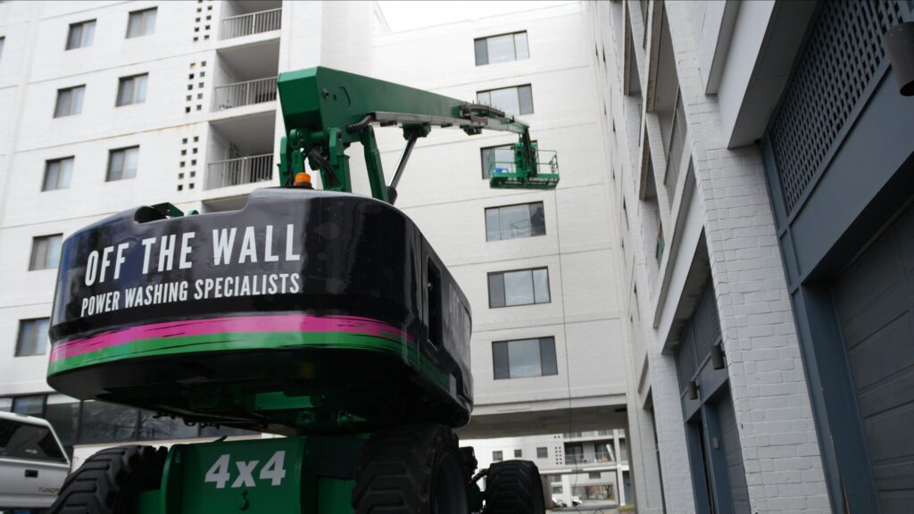 photograph of the OFF THE WALL lift on a job site where a team member is power washing a building exterior