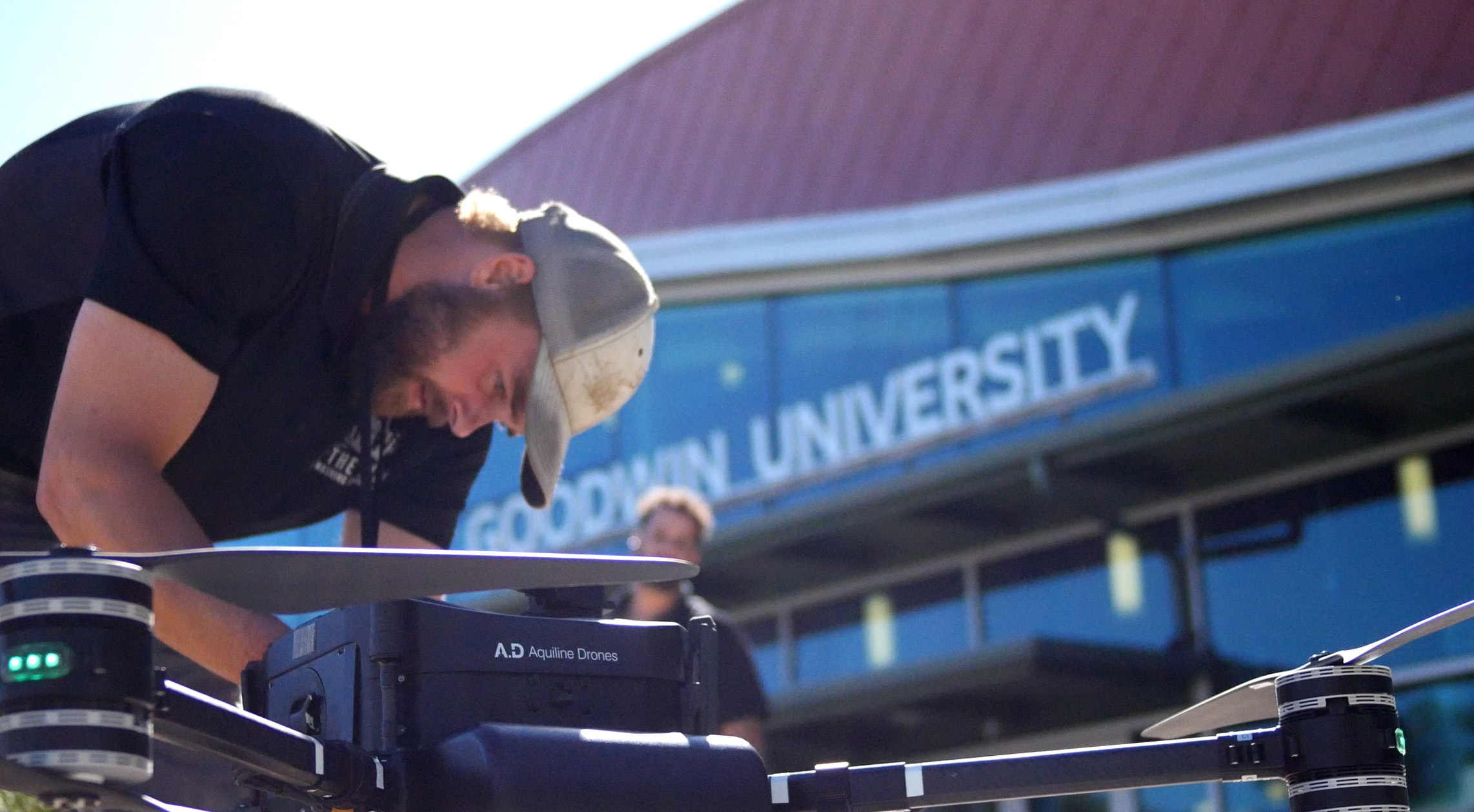 Photo of an OFF THE WALL team member setting up the power washing drone on location at Goodwin University in East Hartford, CT