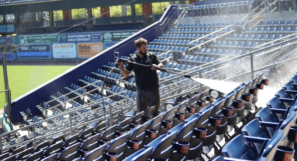 photo of an OFF THE WALL team member power washing the seating at Dunkin Park in Hartford, CT