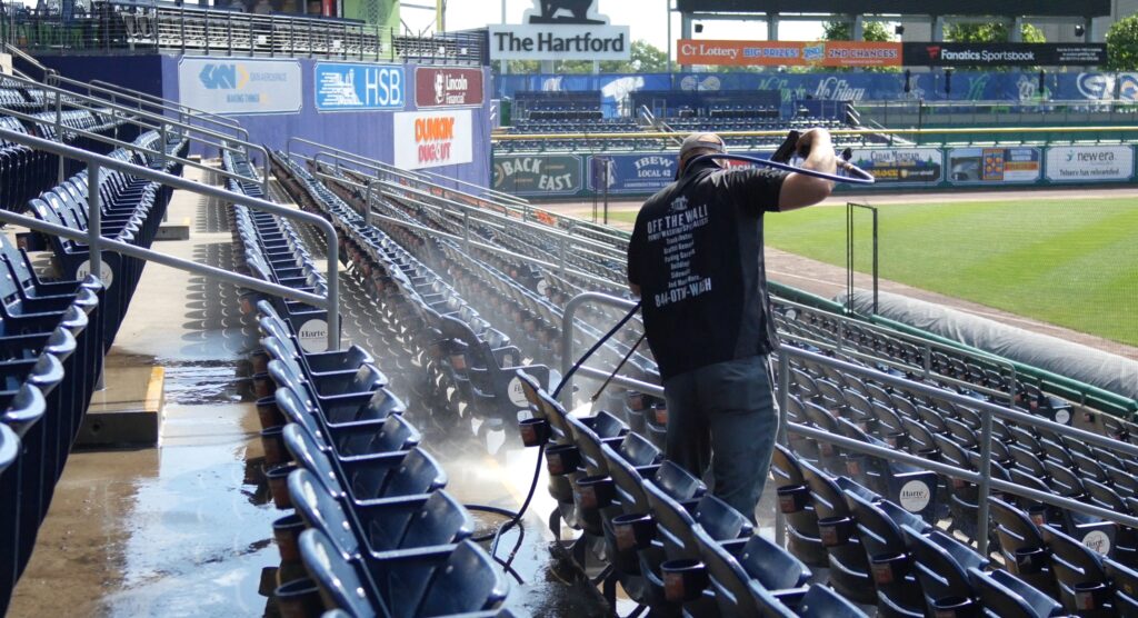 photo of an OFF THE WALL team member power washing the seating at Dunkin Park in Hartford, CT