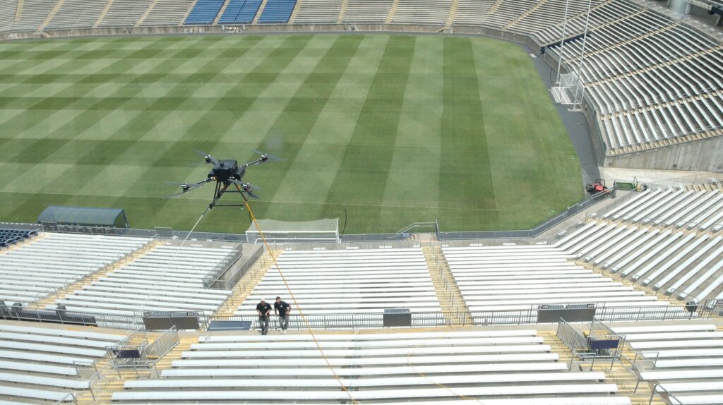 photograph giving a birds-eye-view of the OFF THE WALL team cleaning a stadium with a power washing drone