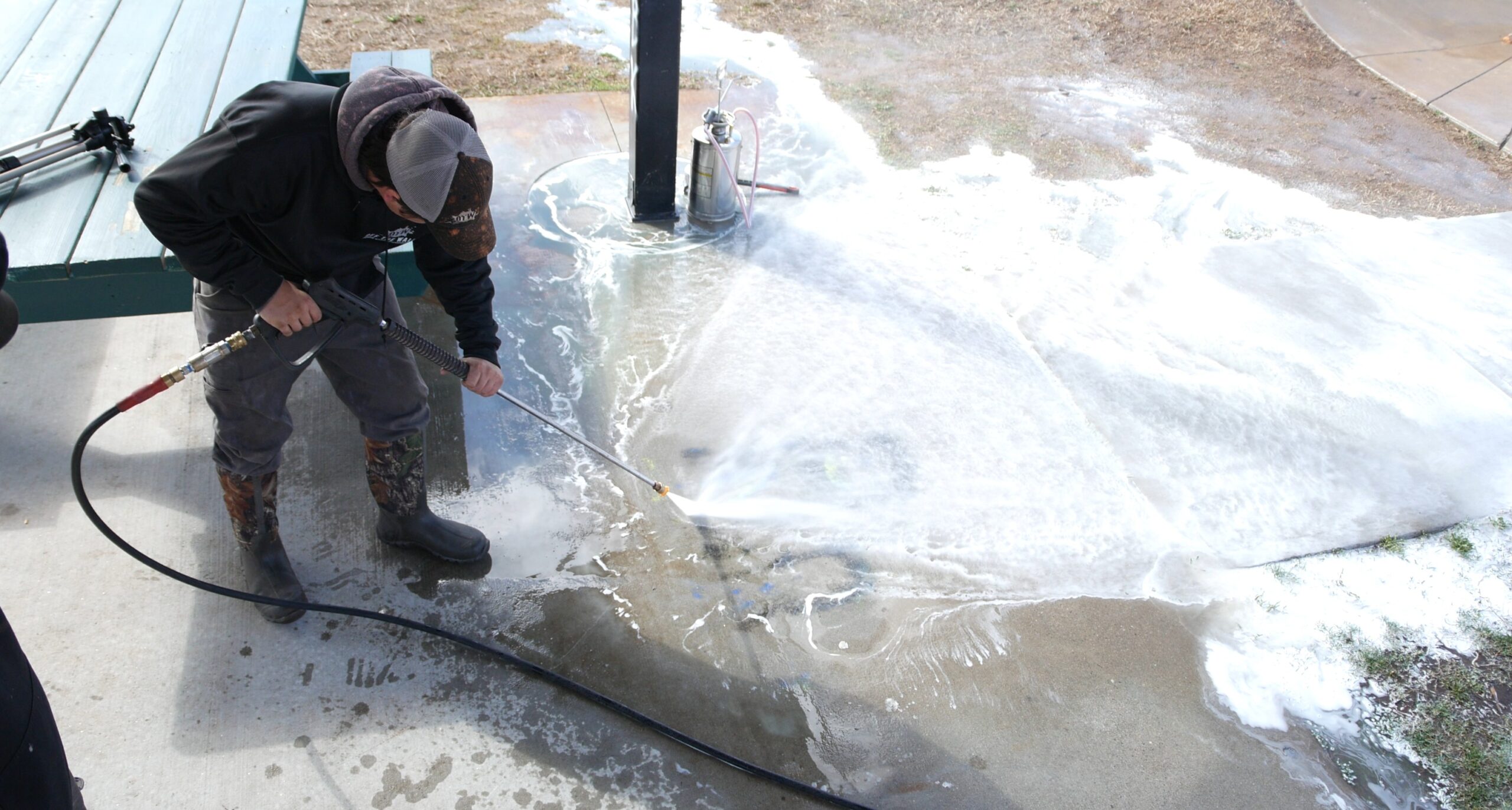 photo of an OFF THE WALL team member removing graffiti from a sidewalk with a power washer
