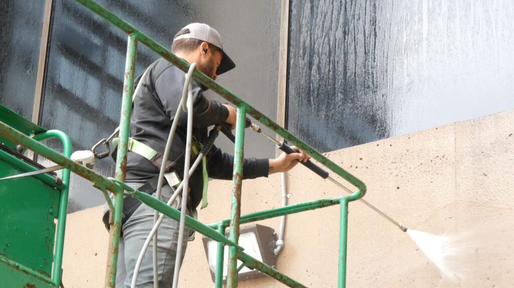 photo of an OFF THE WALL team member on a lift pressure washing the exterior of PeoplesBank Arena in Hartford, CT