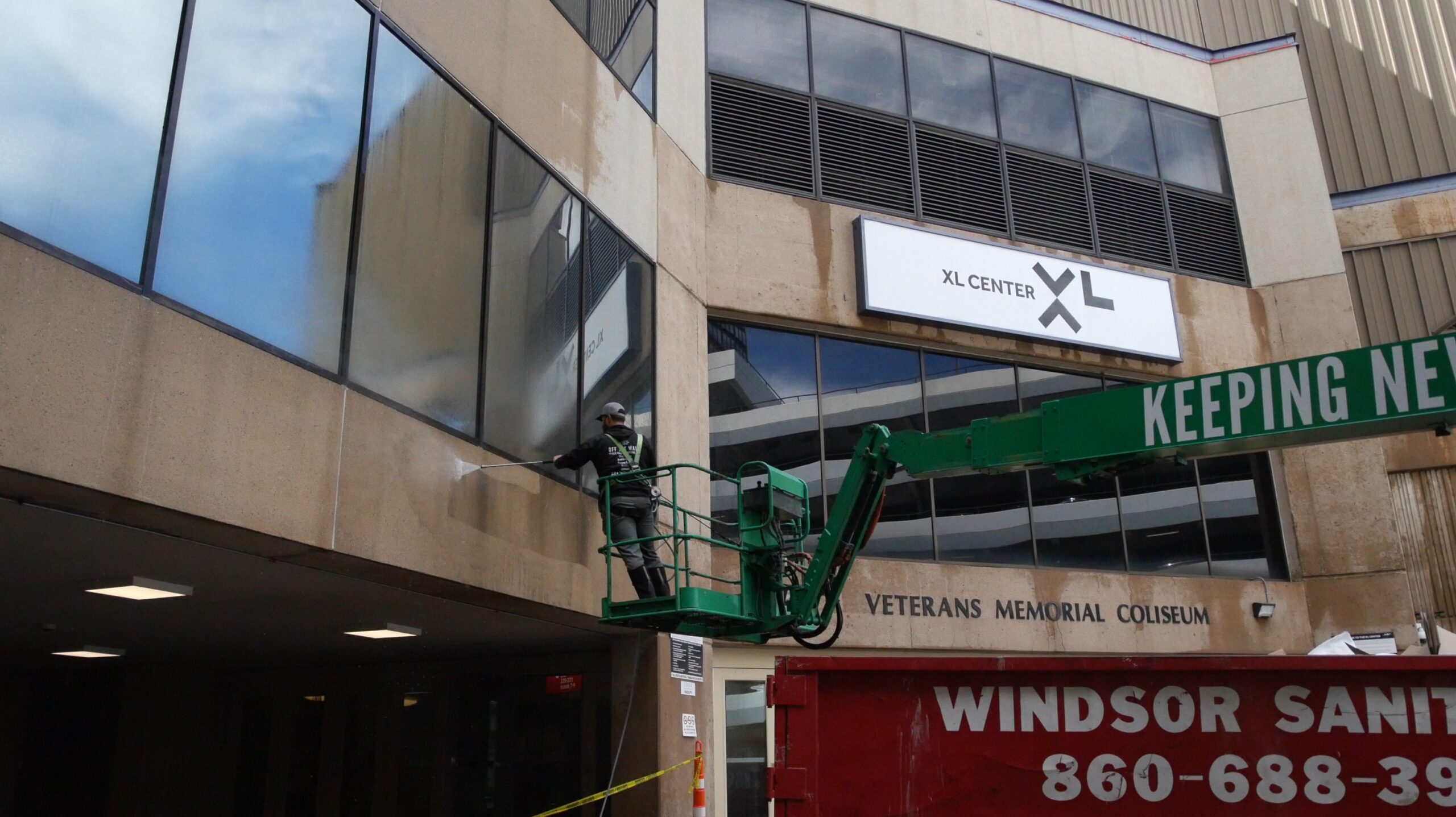 photo of an OFF THE WALL team member on a lift pressure washing the exterior of PeoplesBank Arena in Hartford, CT