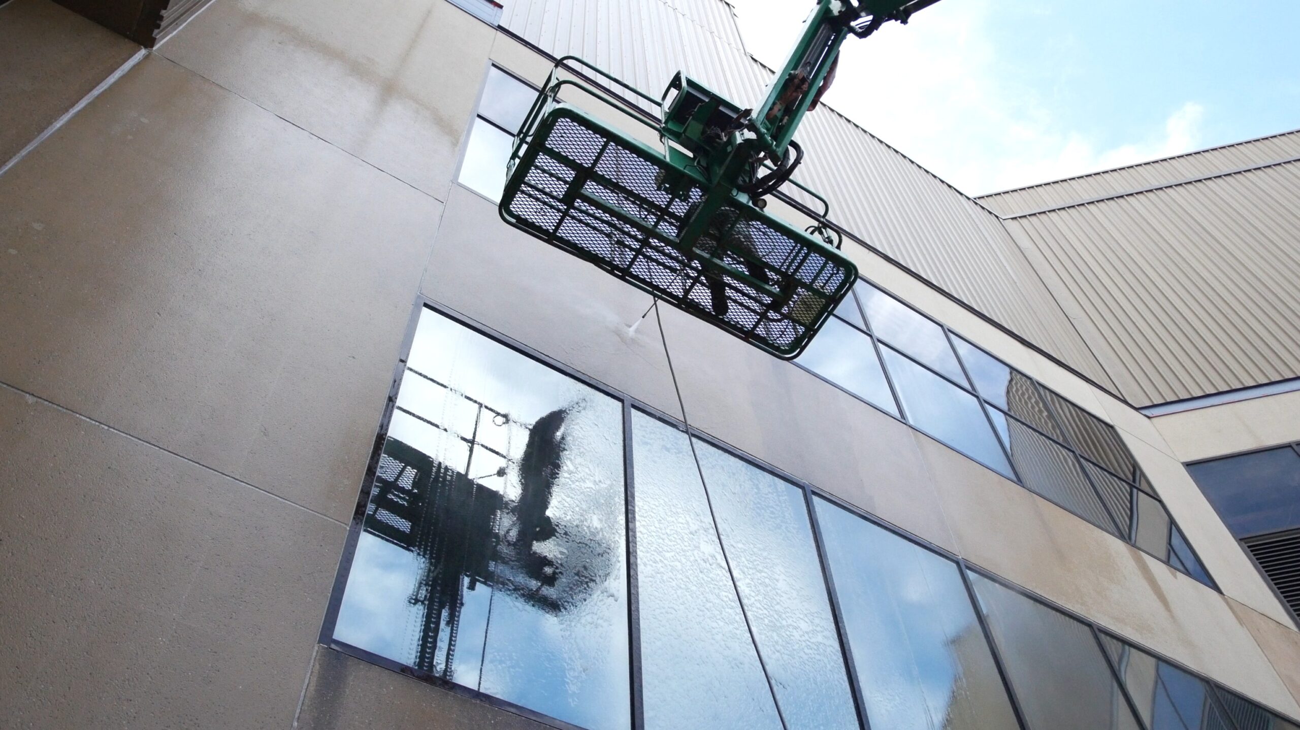 photo of an OFF THE WALL team member on a lift pressure washing the exterior of PeoplesBank Arena in Hartford, CT
