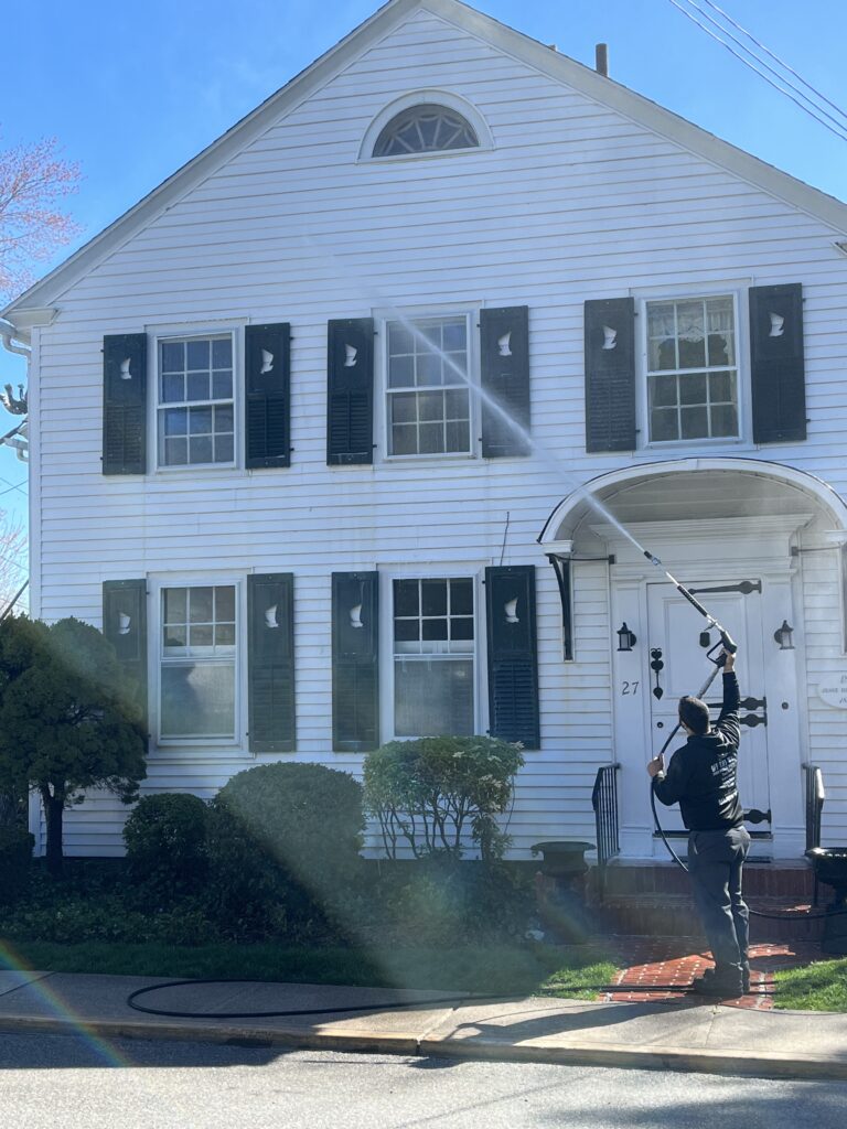 photo of an OFF THE WALL Power Washing team member washing a house