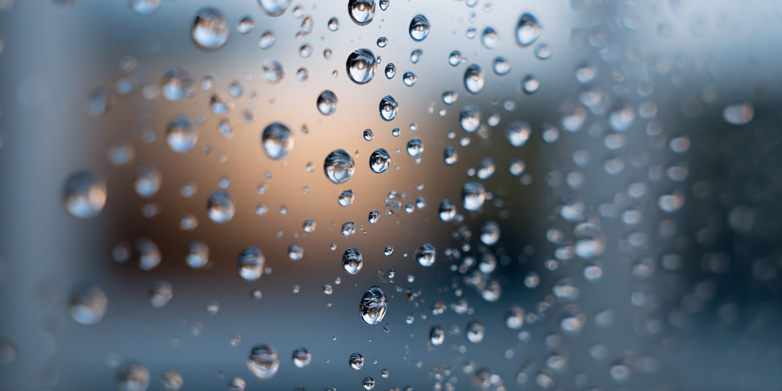 image showing a closeup of water droplets on an apartment building window in winter